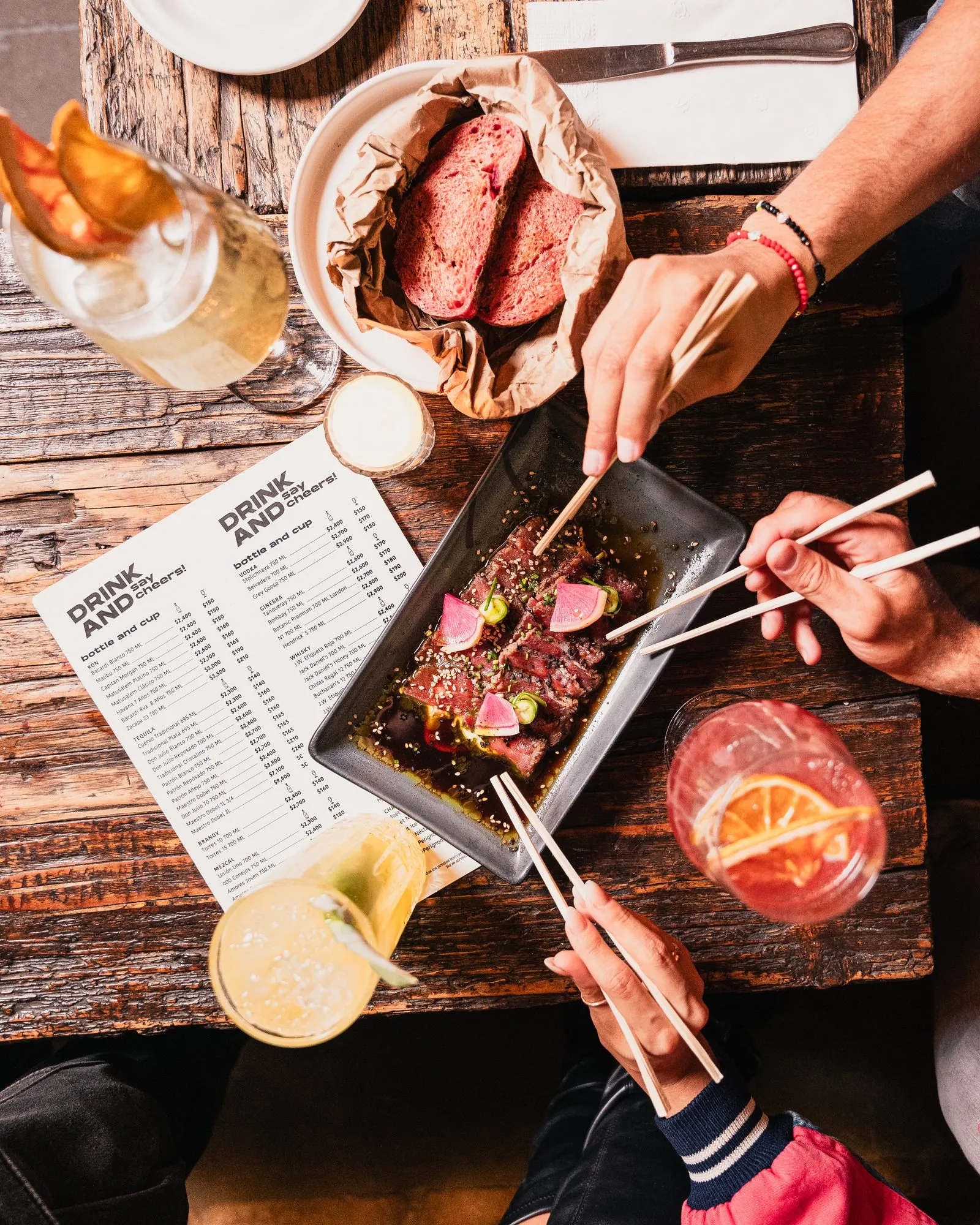 Mesa compartida con carnes, cocteles y carta de bebidas