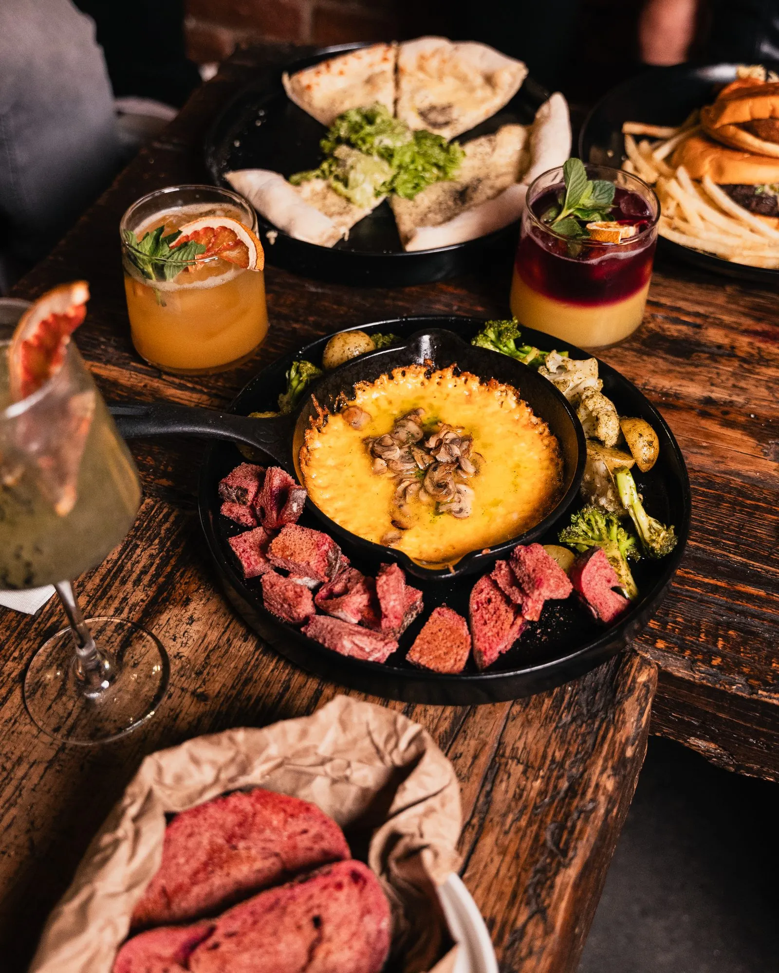 Mesa con carnes, queso fundido y cocteles