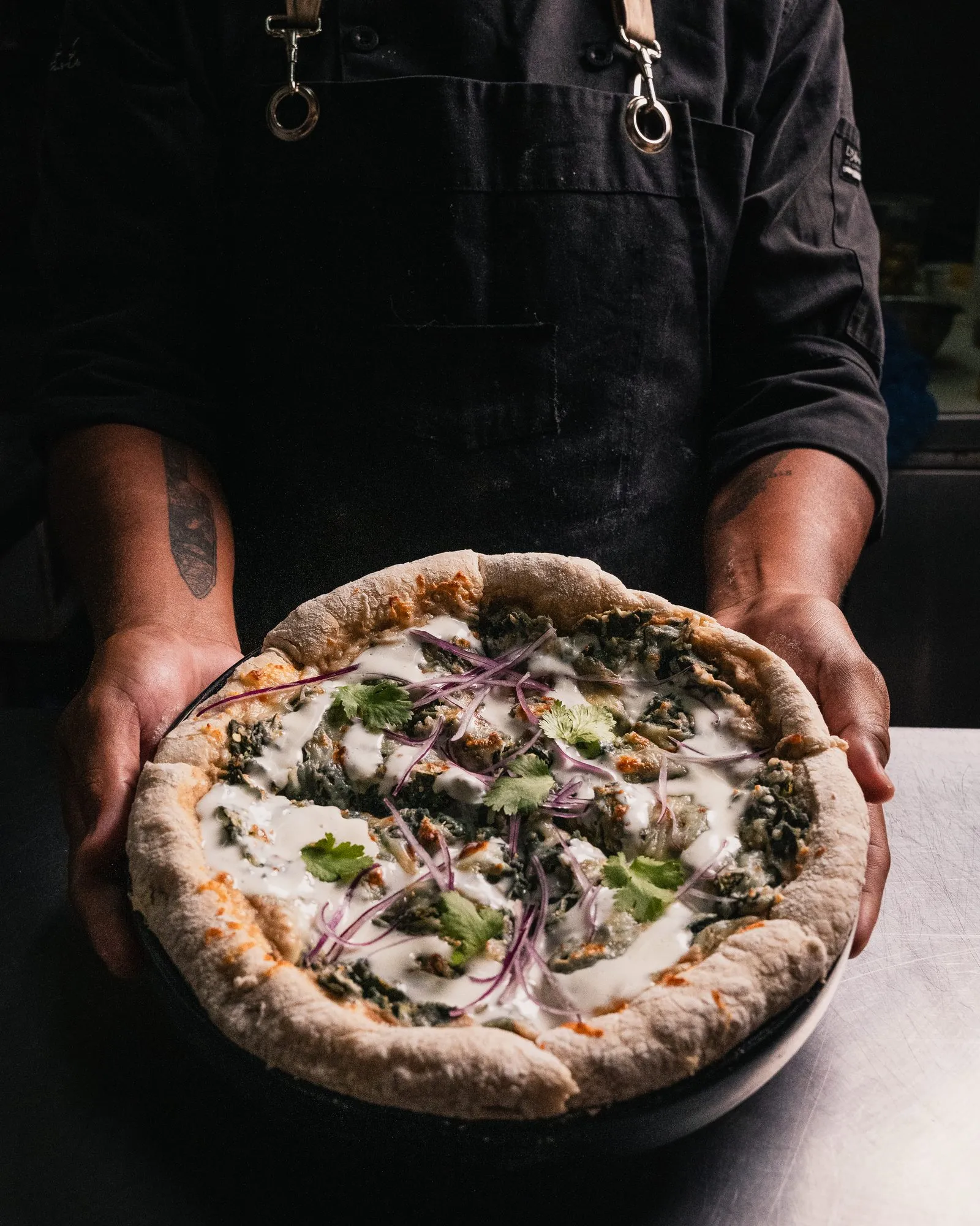 Chef sosteniendo una pizza artesanal